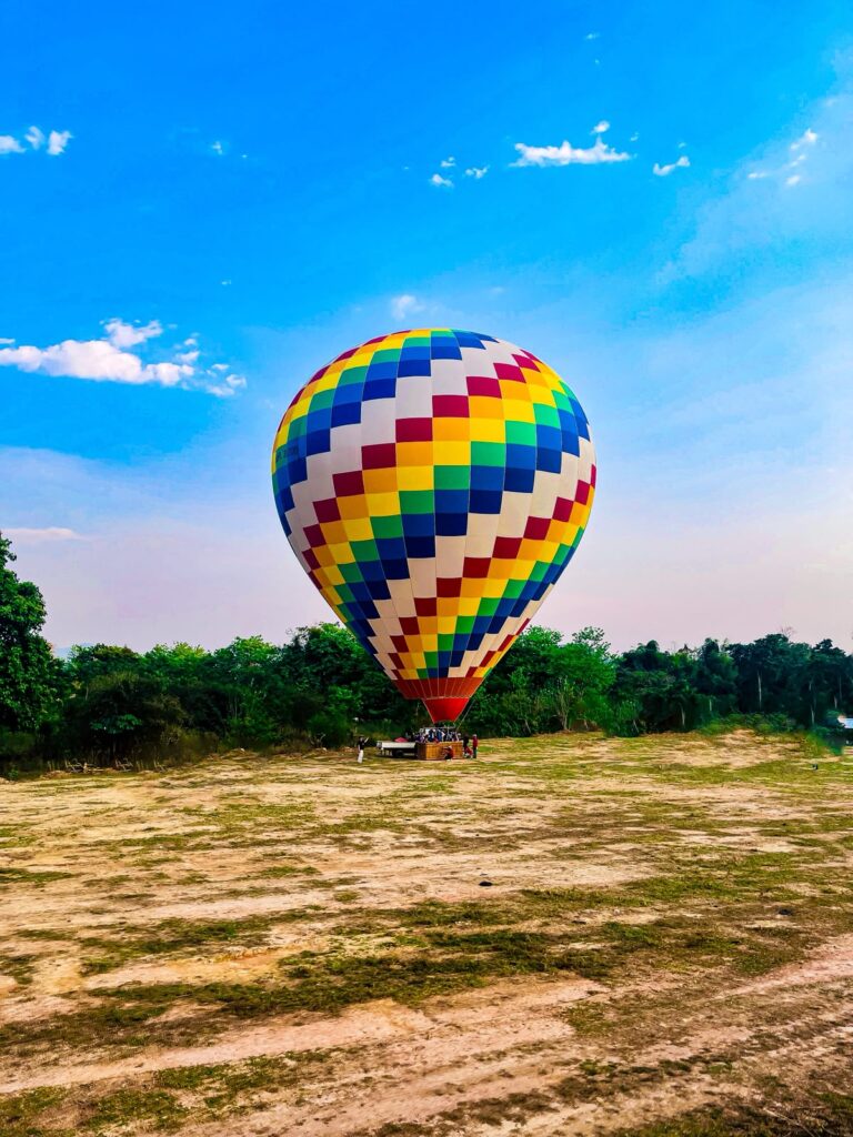 Colorful hot air balloon being prepared for takeoff in a grassy field near Vang Vieng, Laos