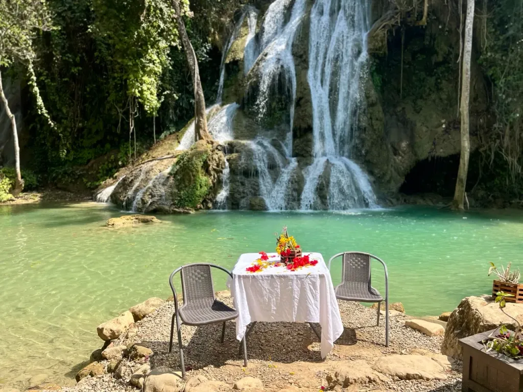Cascading tiers of a turquoise waterfall pool near Luang Prabang, Laos, framed by jungle and hanging vines