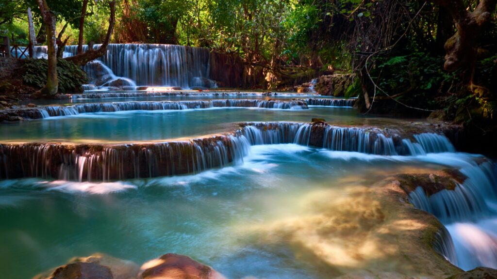 Layered turquoise pools of Kuang Si Waterfall cascading through the forest near Luang Prabang, Laos