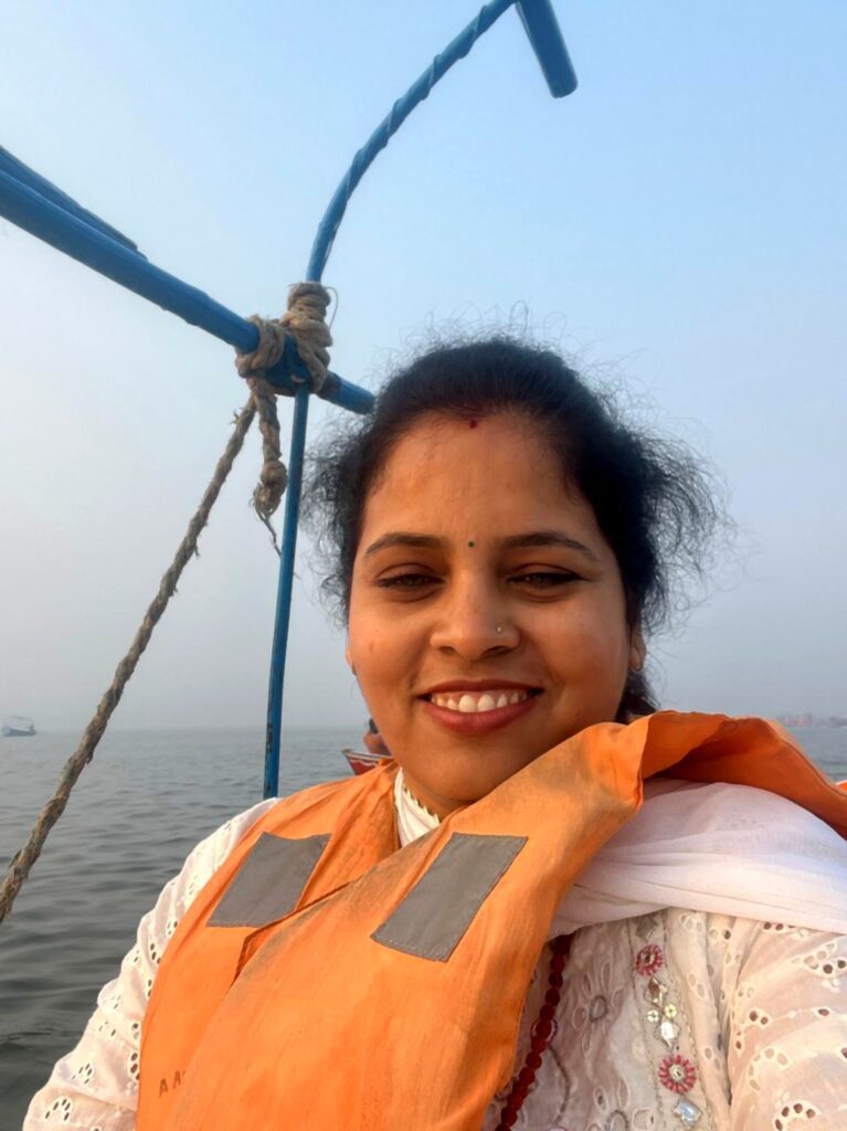 Selfie of a woman smiling on a small boat crossing the Ganges towards the Sangam at Prayagraj during Mahakumbh