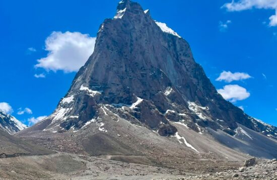 Dramatic rock spire and glacial stream on the Shinkula Pass road to Zanskar Valley